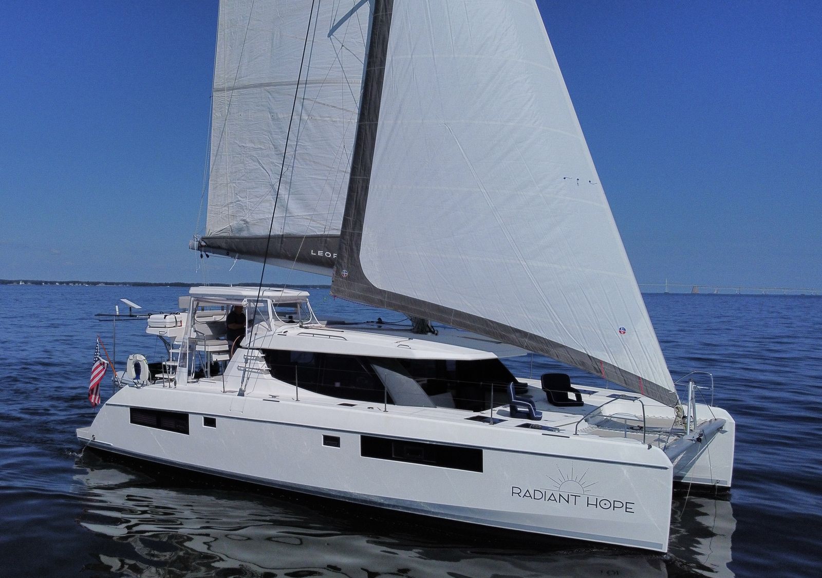 Bow-quarter under sail toward Bay Bridge, forward cockpit seats visible