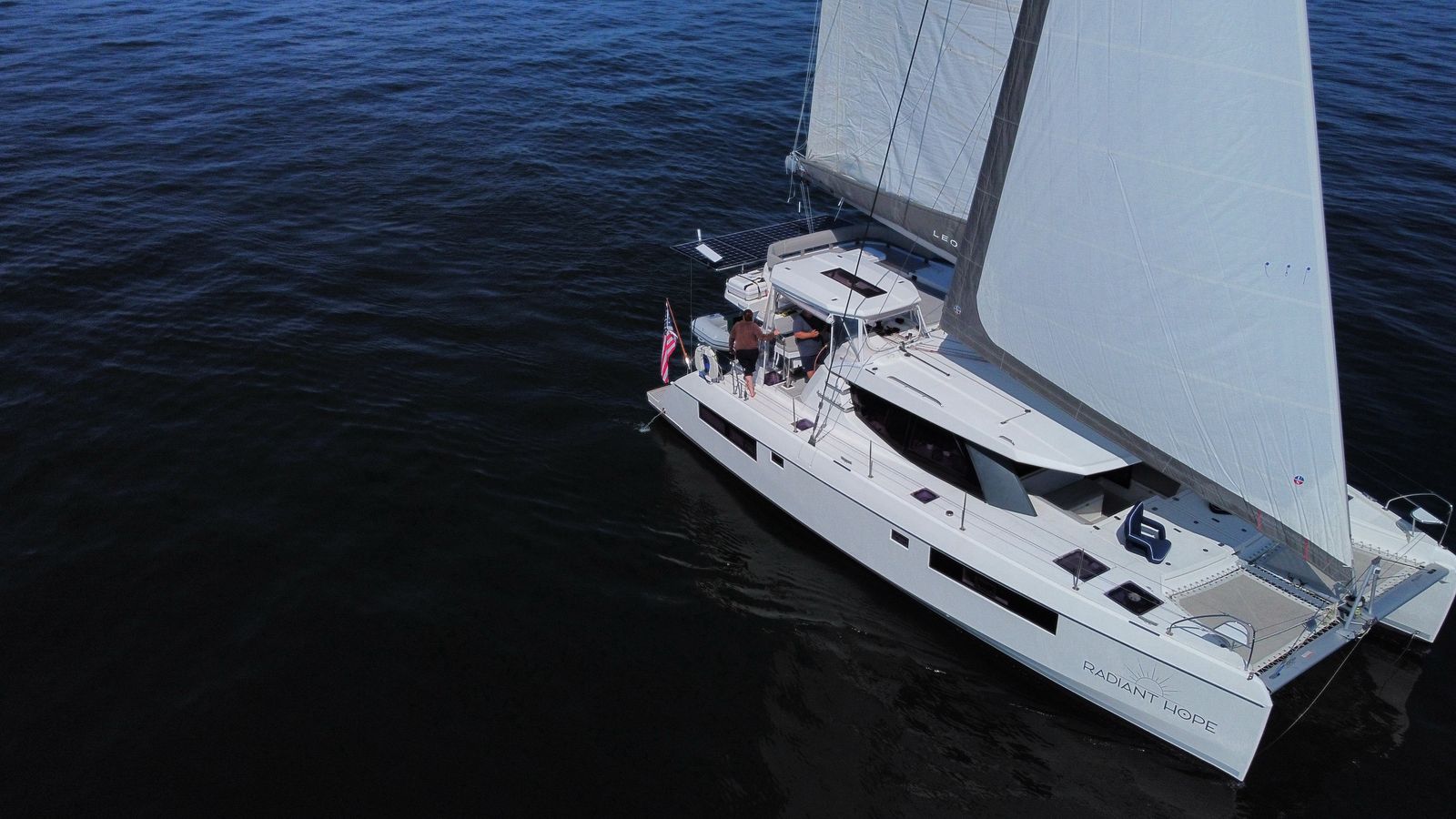 Higher drone angle of Radiant Hope under sail, name on aft hull