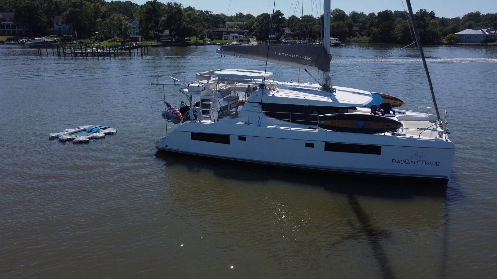 Drone view of catamaran at anchor near shore and pond
