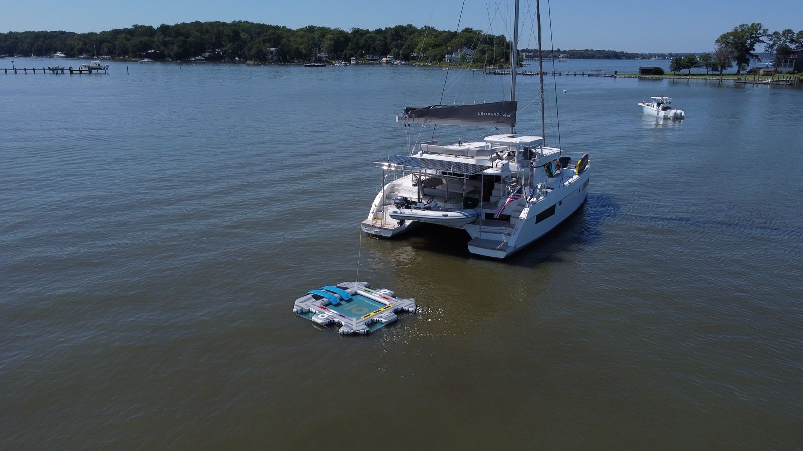 Stern-quarter aerial of full-width solar rack, stackpack, and dinghy